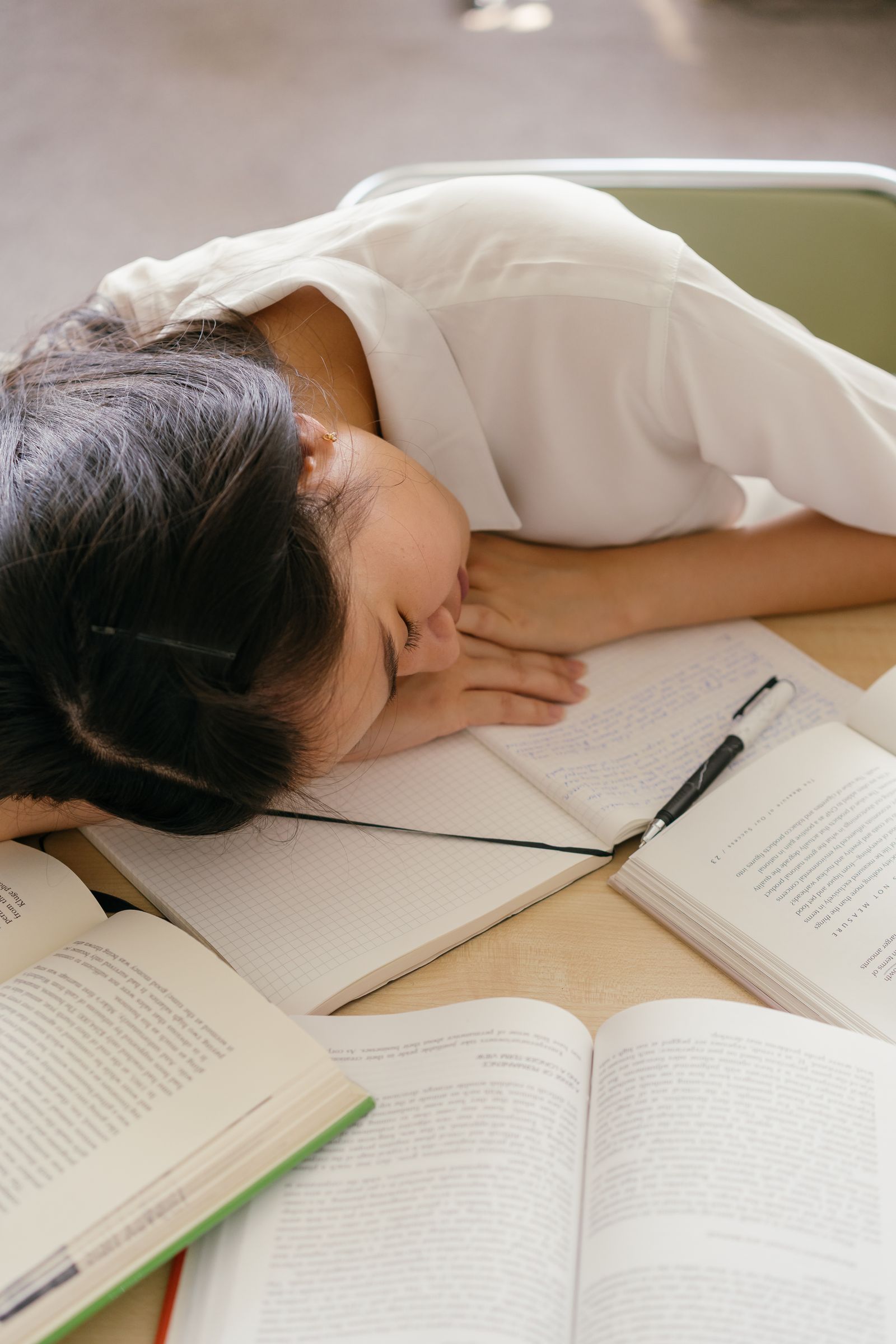 教科書の上に突っ伏して寝てしまっている様子